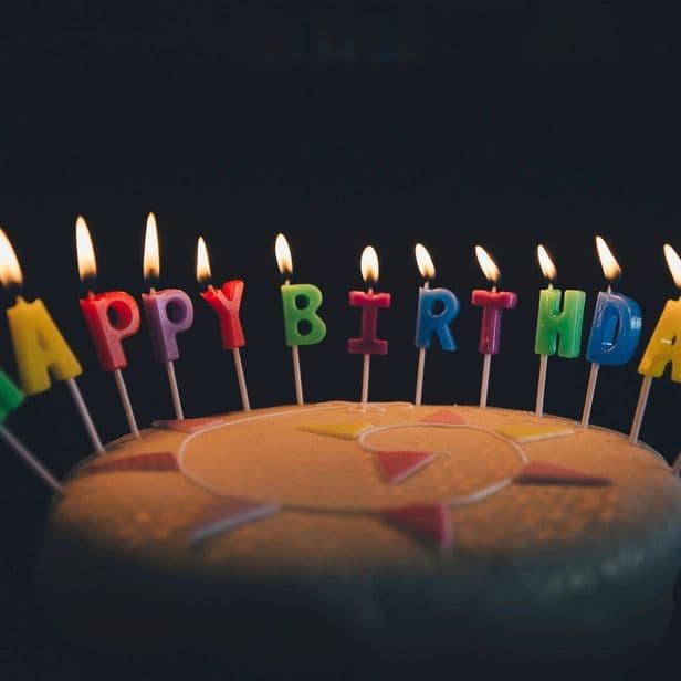 Lit birthday candles spelling happy birthday on a cake