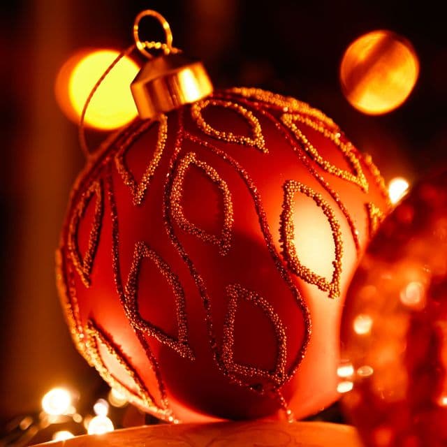 A red ornament glowing in warm holiday light