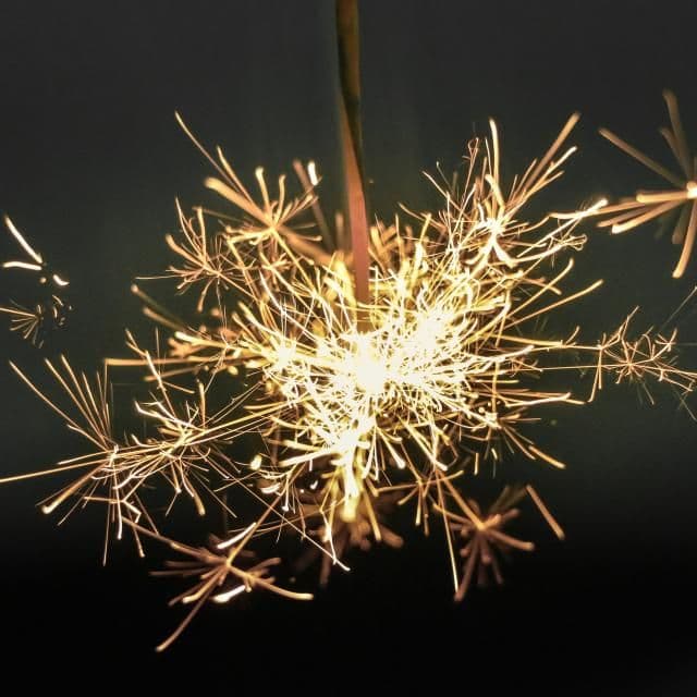 A lit sparkler glowing against the night
