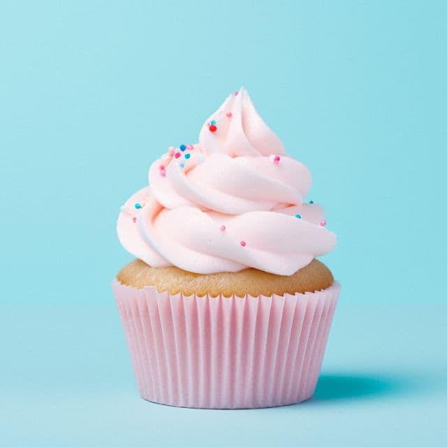 A pink-frosted sprinkle cupcake on a bright aqua background