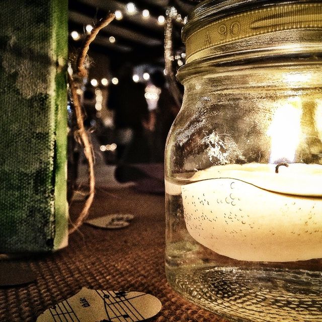 A candle glowing in a mason jar at an evening reception