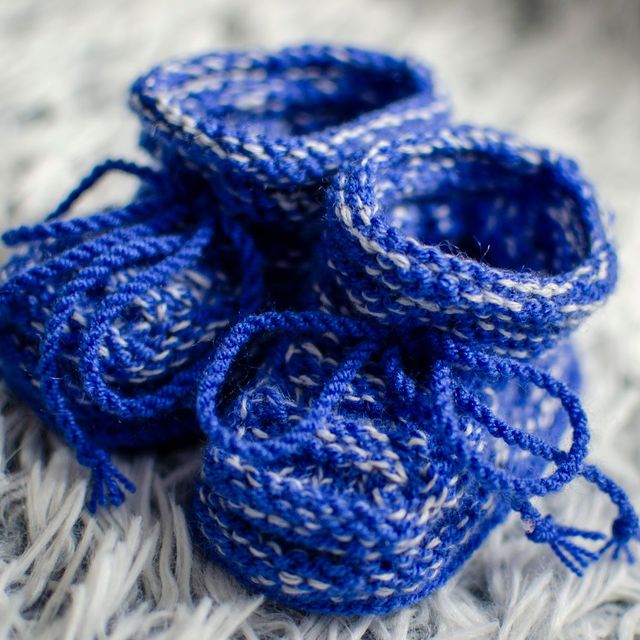 Blue knitted baby booties on a fleece blanket