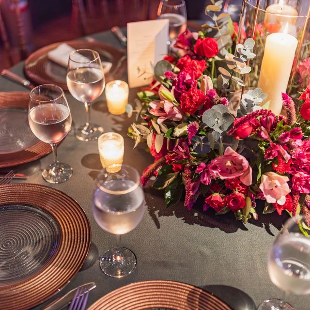 A dinner table set with deep pink flower centerpieces