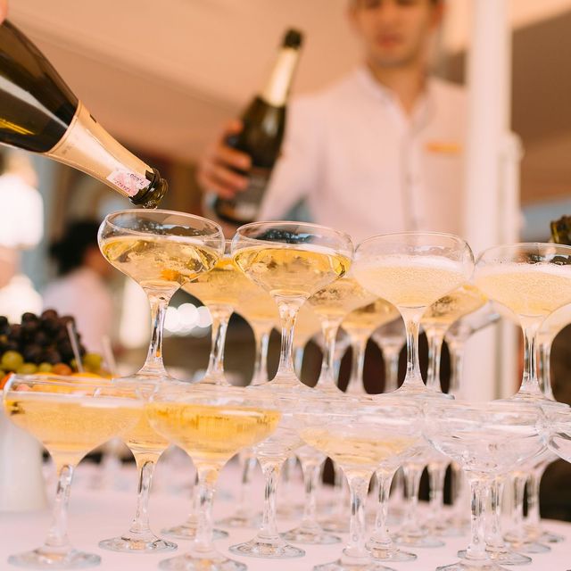 A champagne tower being poured at an outdoor celebration