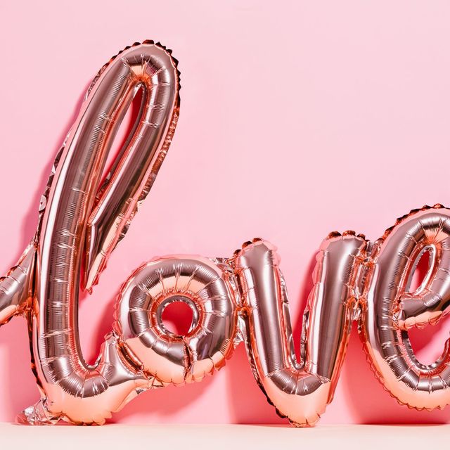 A rose-gold LOVE balloon against a pink wall