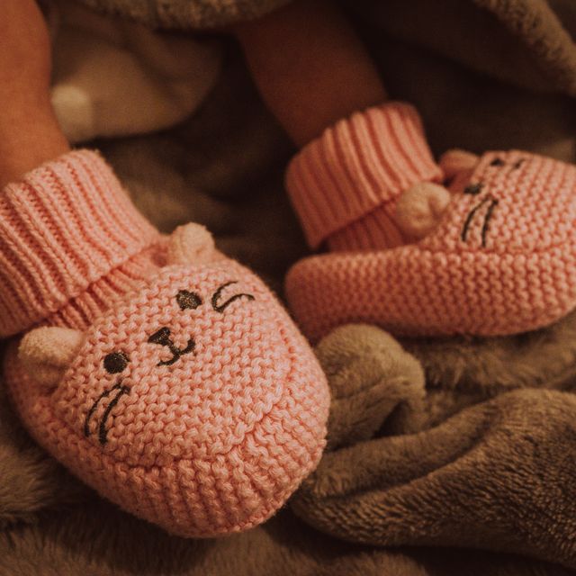 Pink knitted baby booties on soft wool